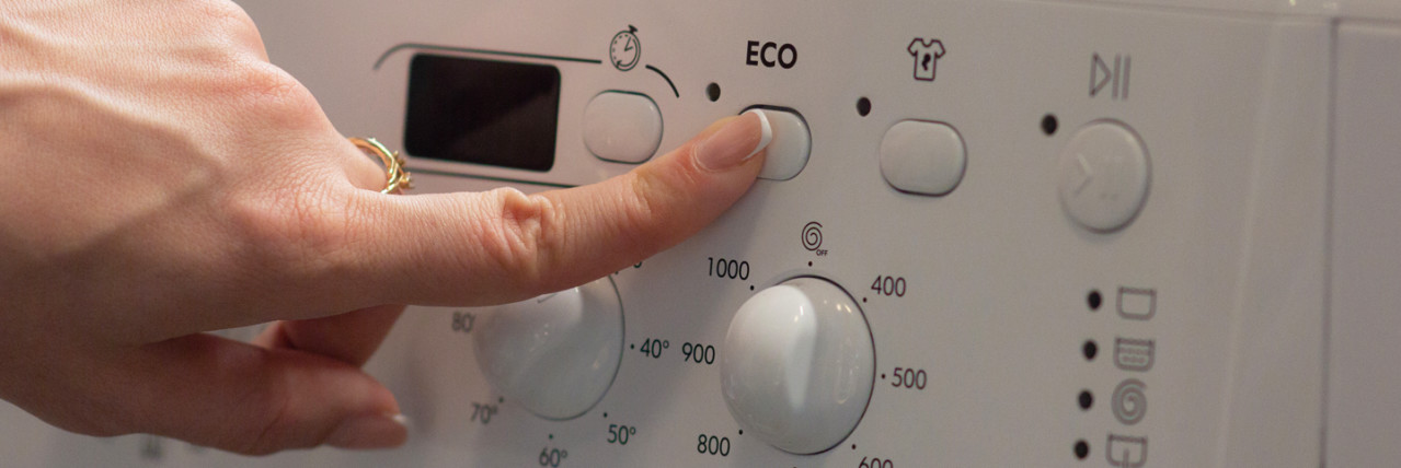 Person clicking the eco button a washing machine