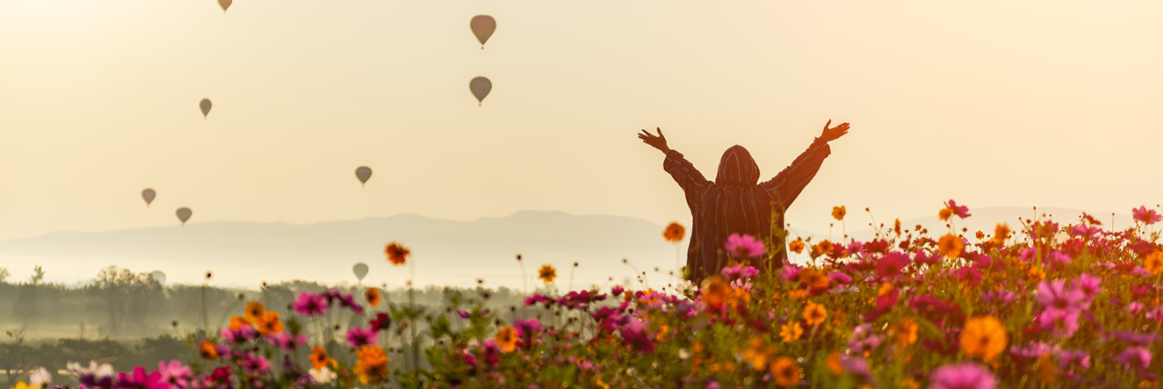 Person in a field with hot air balloons in the background